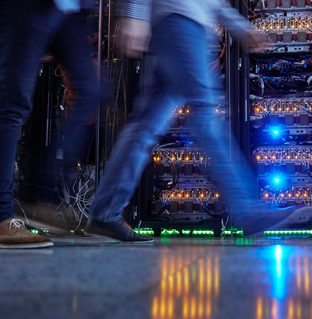 Dos operadores de red pasan rápidamente por sus equipos de red automatizados, lo que hace que sus piernas aparezcan borrosas. Dos operadores de red pasan rápidamente por sus equipos de red automatizados, lo que hace que sus piernas aparezcan borrosas.